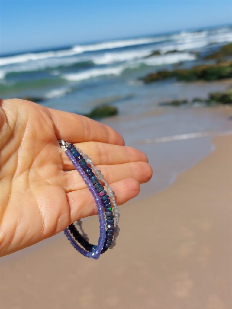 Fioletowo-niebieska bransoletka z kamieni na dłoni na plaży