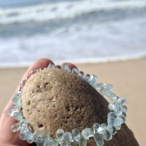 Bransoletka akwamaryn – na dłoni z kamieniem na plaży